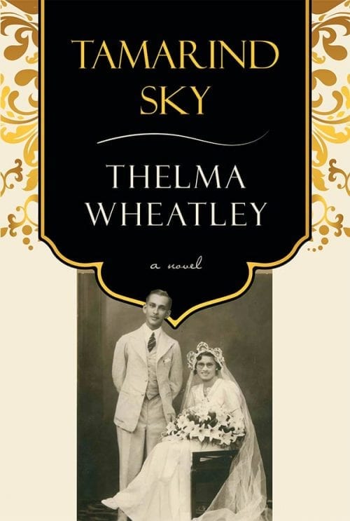 book cover: white background with gold floral designs in the upper half. A vintage photo featuring a standing South Asian groom in a suit and a seated white woman in a wedding dress holding a bouquet. A black banner features block gold text "Tamarind Sky" and "a novel". The author's name, Thelma Wheatley, appears in white block text below.